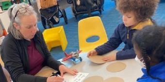 An adult reads with two children at a table