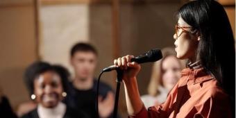 A woman speaks into a microphone and audience claps