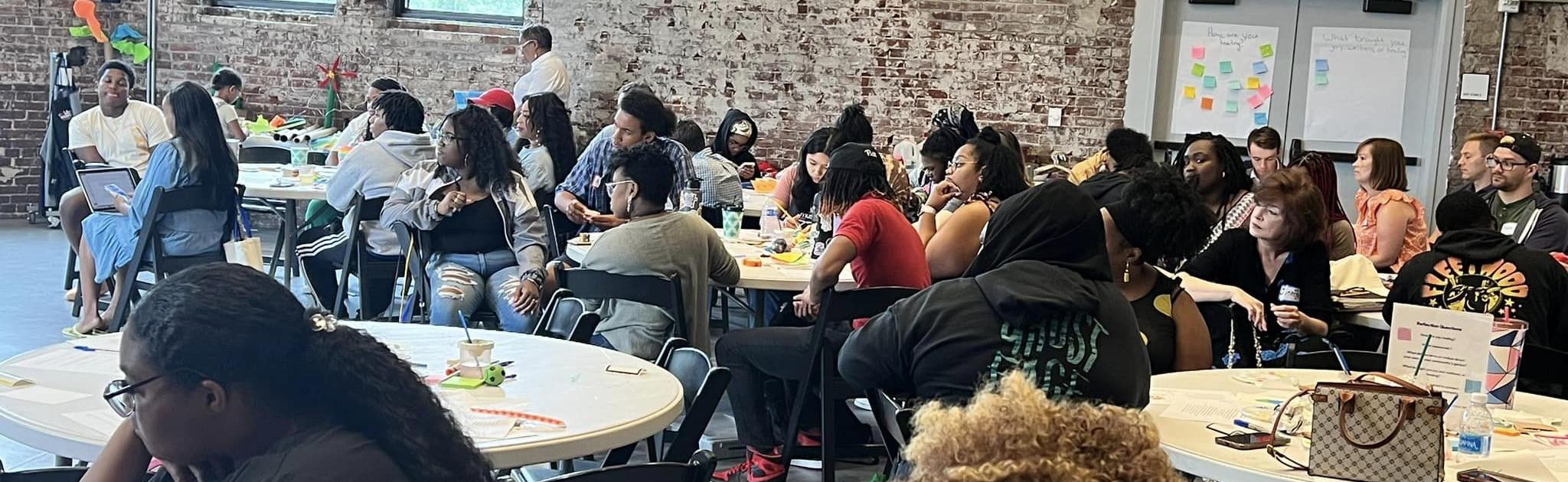 Large group of educators sit at tables during presentation