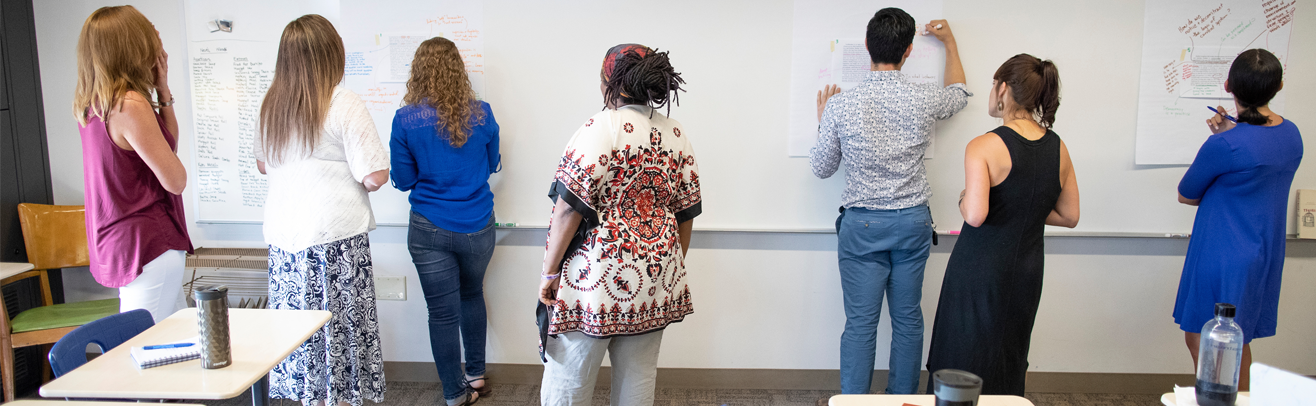 a group of people in front of a white board